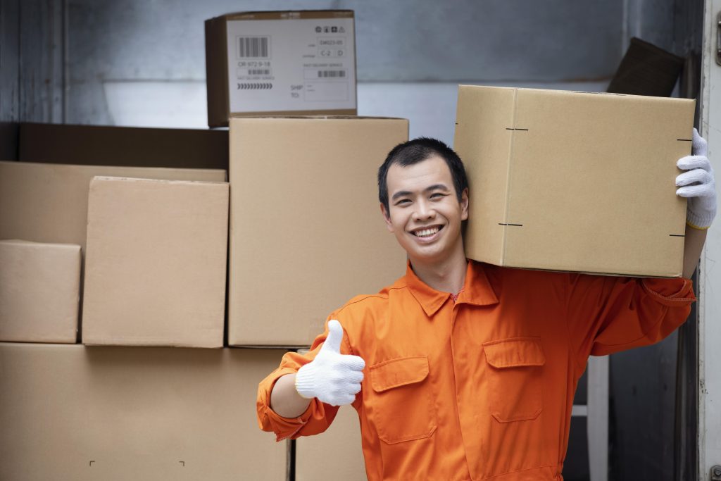 This image shows a Philippines Top 5 Features of a Modern WMS warehouse worker carrying a package with confidence and giving a thumbs-up—symbolizing efficiency, accuracy, and satisfaction.