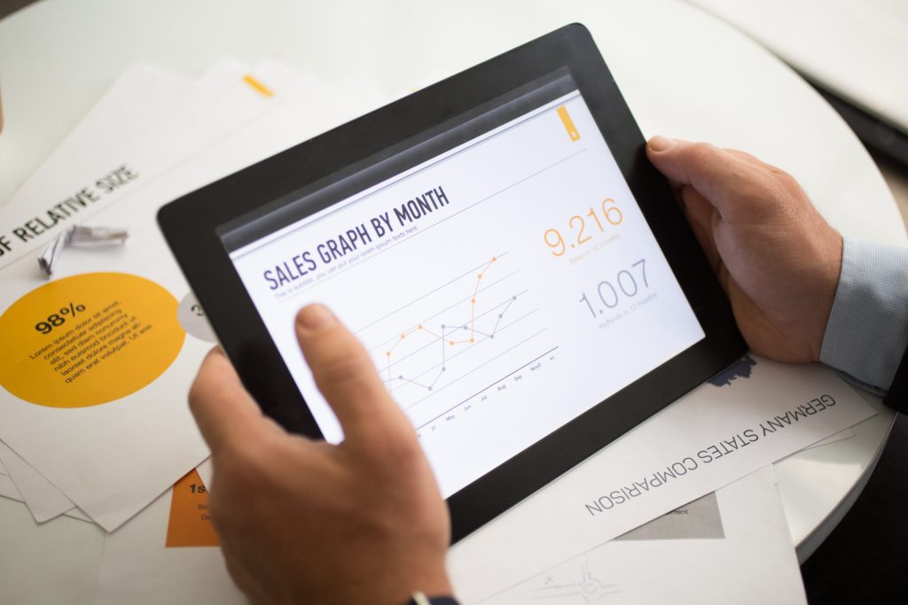 Sales graph on tablet screen. Close-up of Wholesales Inventory Management Software. Unrecognizable businessman using digital tablet at table with papers. Progress concept
