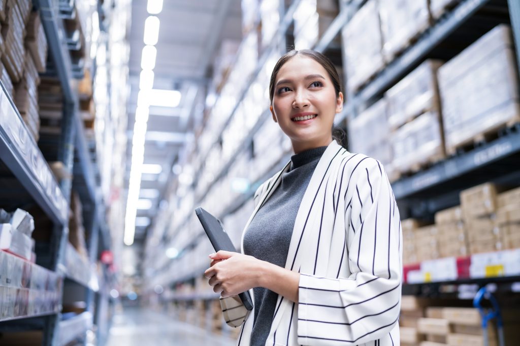Portrait of asian woman business owner using digital tablet checking amount of stock product inventory on shelf at distribution warehouse factory.logistic business shipping and delivery service