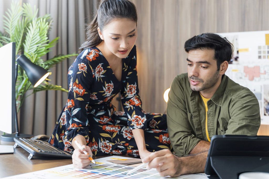 young asian and caucasian adult creative partnets working with new project discussion brainstorm in office day time,meeting of designer partners conversation with focus and concentrate